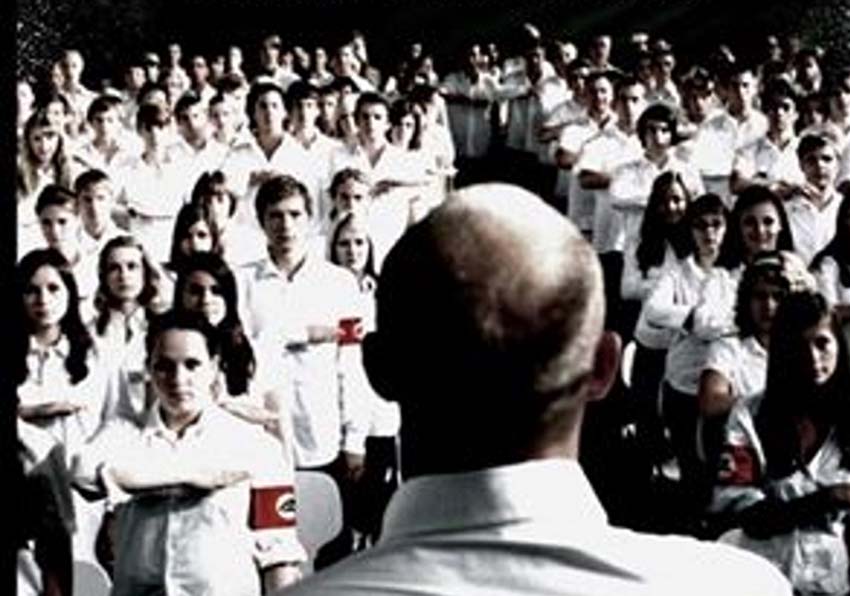 event image:Poster detail. A man with his back turned talking to a group of young people